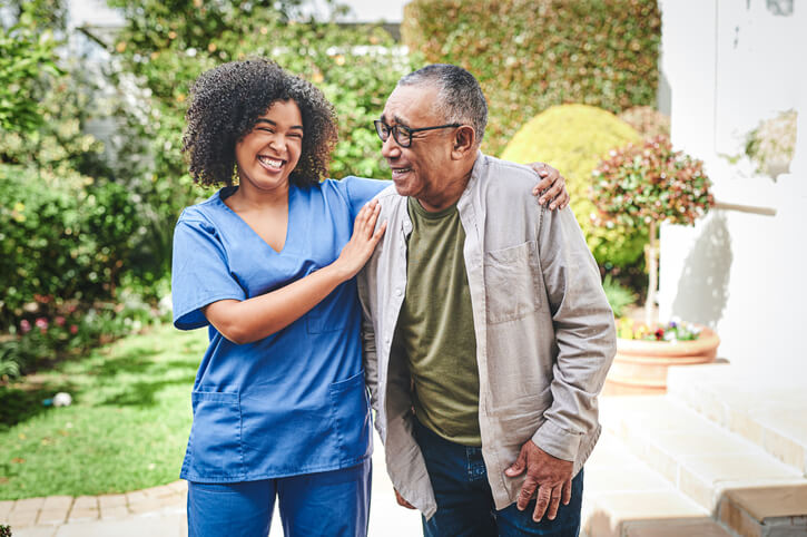 Shot of beautiful, smiley young black nurse bonding with her senior black male patient outside of what looks to be some type of senior living facility. The image is shown related to our Braintree MA's elder law services, including long term care planning.