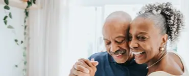 This is the image of a very attractive black couple -- a man with a black mustache and a woman with her curly gray and black here up. She is wearing beautiful earrings and a nice ivory colored dress. They appear to be celebrating some occasion. The image is shown to support the fact that our Braintree MA estate planning and probate services firm can help with all your long term planning needs, including creating a last will and testament.