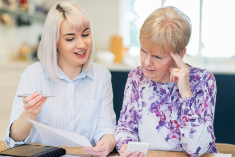 Image Of A Younger Woman Helping What Appears To Be Confused Senior With Paperwork. The image is shared in keeping with our estate planning law firm's blog post about financial conservatorship.