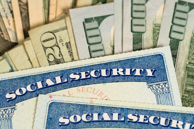 USA Social Security cards laid on pile of dollar bills